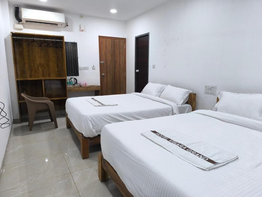Habitación de hotel con dos camas, un armario de madera, un escritorio y una silla.