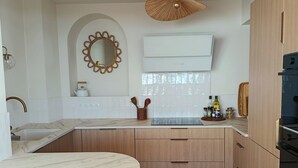 A modern kitchen with a round marble countertop, wooden cabinets, a hanging light fixture, and a built-in oven. - SUPERB T4 SEAFRONT WITH ROOFTOP IN ST JEAN DE MONTS (Saint-Jean-de-Monts)