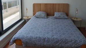 A modern bedroom with a large bed, a ceiling fan, and a view through a large window. - SUPERB T4 SEAFRONT WITH ROOFTOP IN ST JEAN DE MONTS (Saint-Jean-de-Monts)