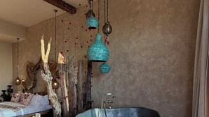 A spacious room with a large bathtub, wooden furniture, and hanging lights.
