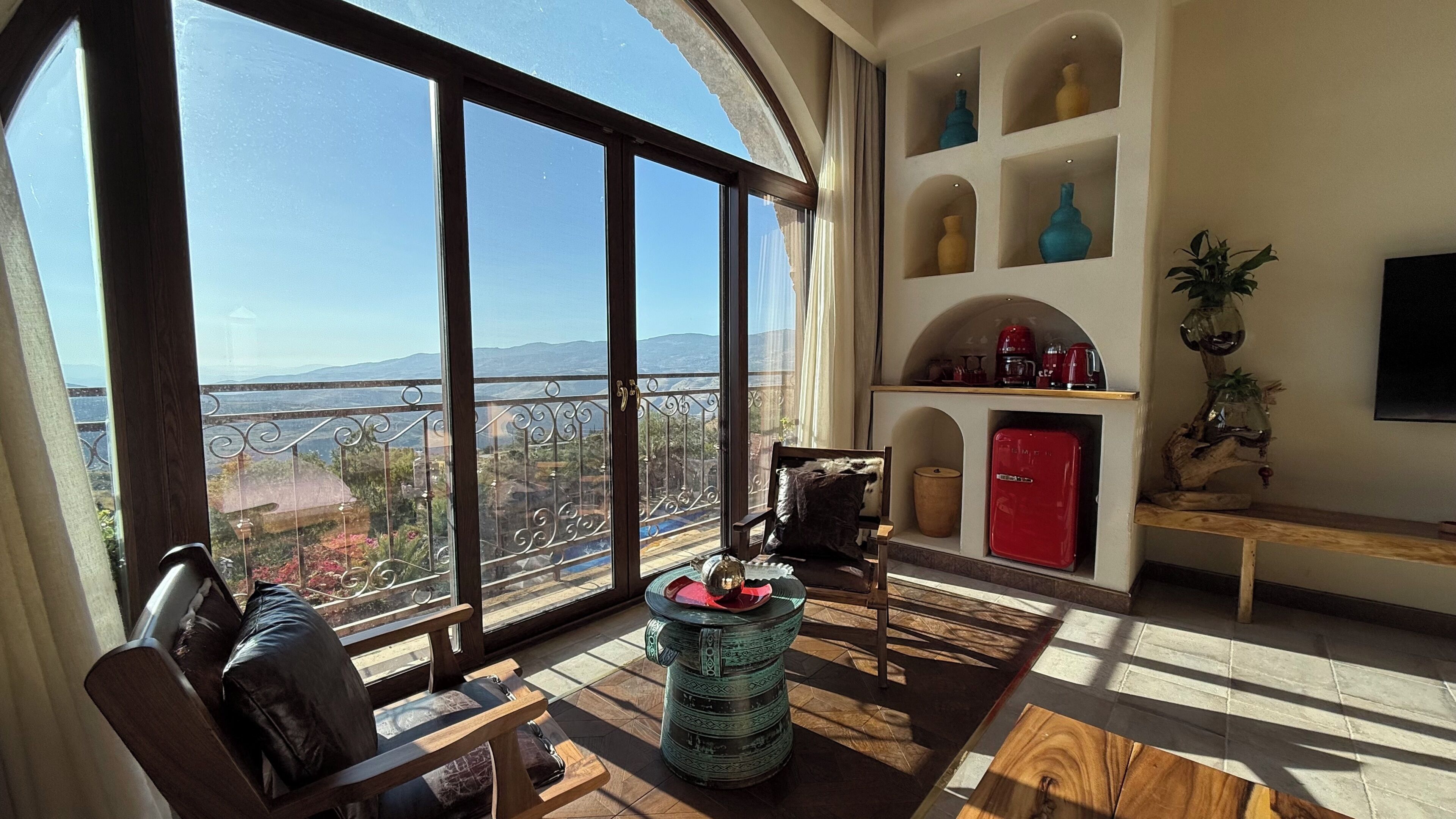 A spacious living area with large windows, a red refrigerator, and a view of the mountains.