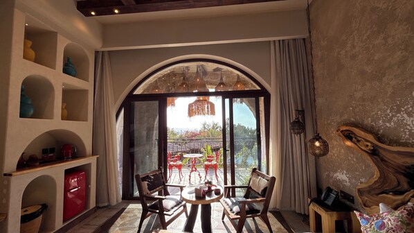A room with a large arched window, a round table with chairs, and a view of the outdoors.