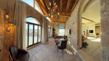 A spacious interior with stone walls, large arched windows, and hanging decorative lights.