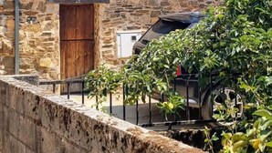 Un bâtiment en pierre avec un toit en pente, une porte en bois et une petite fenêtre.