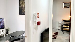 Ein modernes Wohnzimmer mit einer Couch, einem Fernseher und einem Essbereich mit Stühlen und einem Tisch.