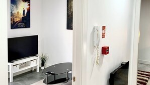 Ein modernes Wohnzimmer mit Flachbildfernseher, einer Couch, einem Couchtisch und einem Kamin.