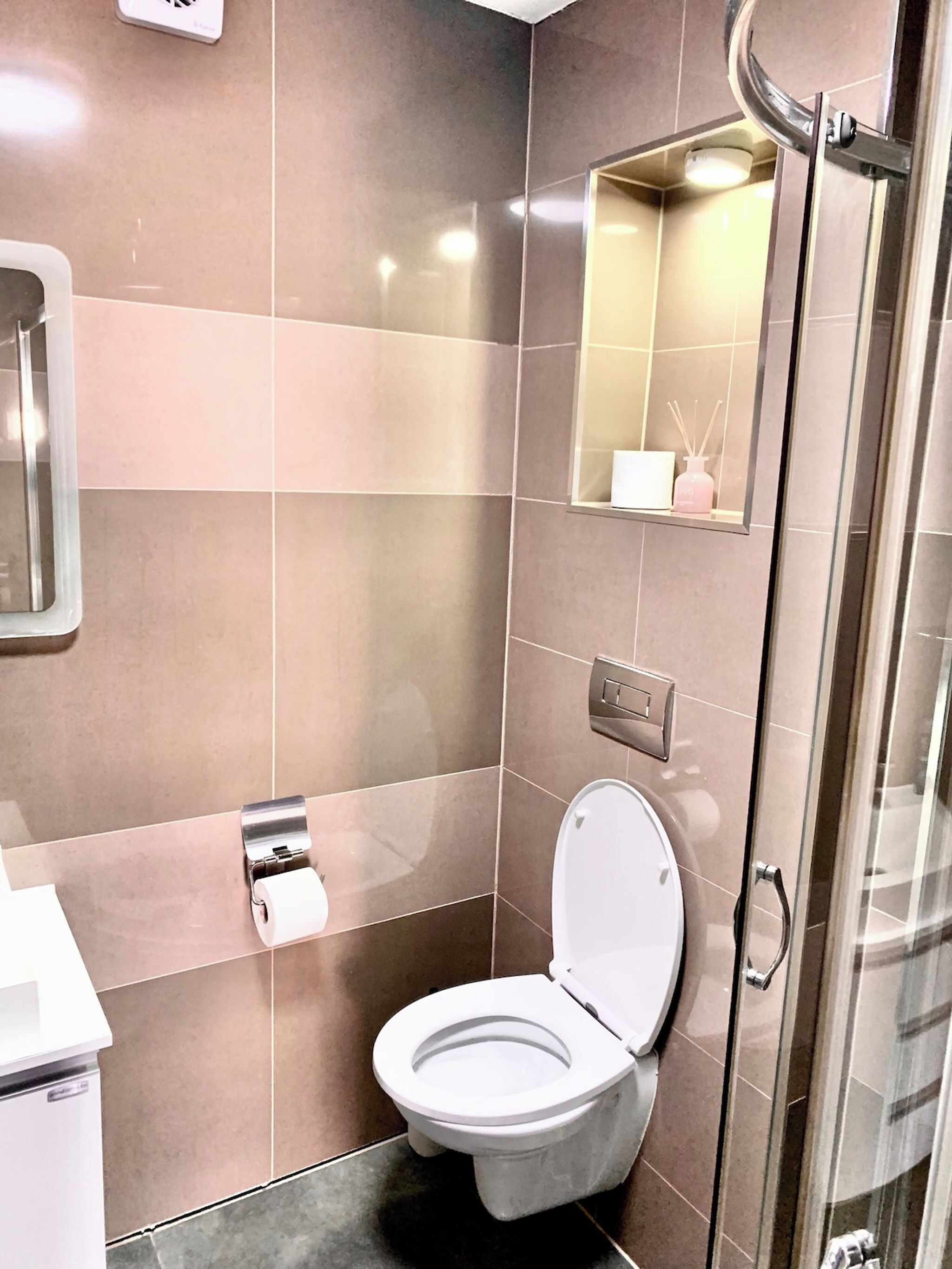 Un baño moderno con inodoro, secamanos y espejo.