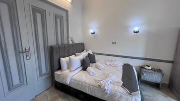 A hotel room with a bed, bedside table, and two wall-mounted lights.