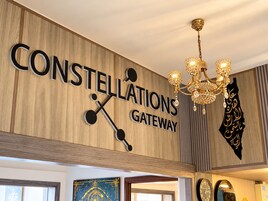 Sinal com a inscrição 'CONSTELLATIONS GATEWAY', design de constelação de estrelas e um candelabro.