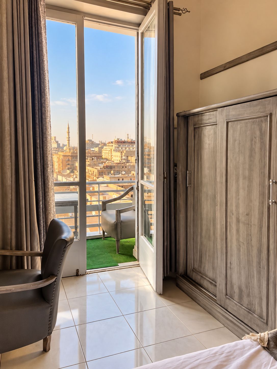 Ein Zimmer mit einer großen SchiebeglasTür, die auf einen Balkon mit Blick auf eine Stadtlandschaft führt.