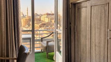 A room with a large sliding glass door leading to a balcony with a view of a cityscape.
