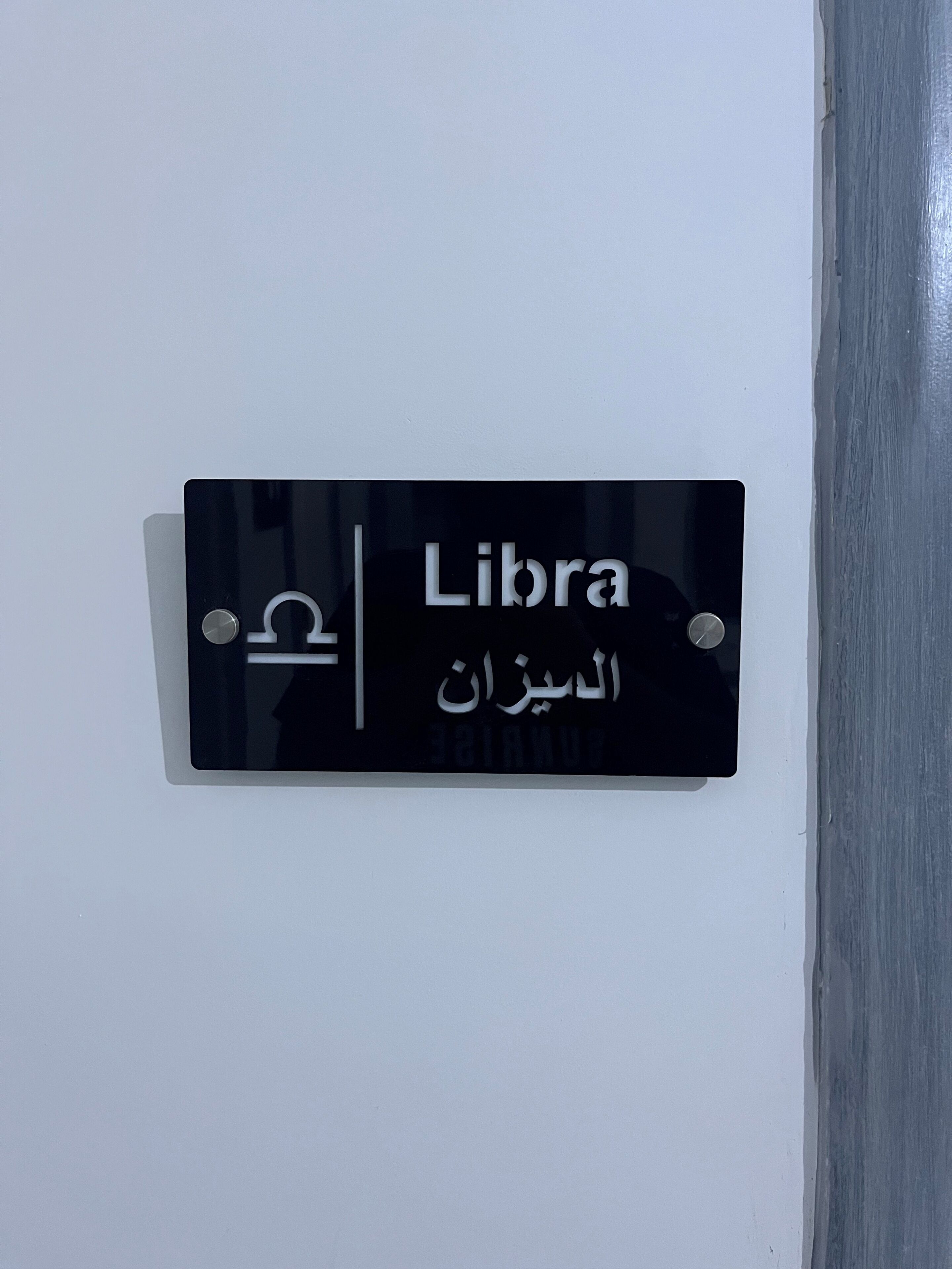 Un segnale nero con testo bianco che recita 'Libra' e scrittura araba sottostante.