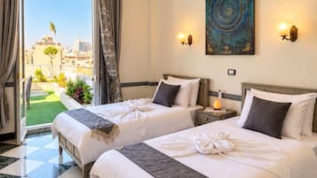 A hotel room with two beds, a ceiling fan, a painting, and a view of the city.
