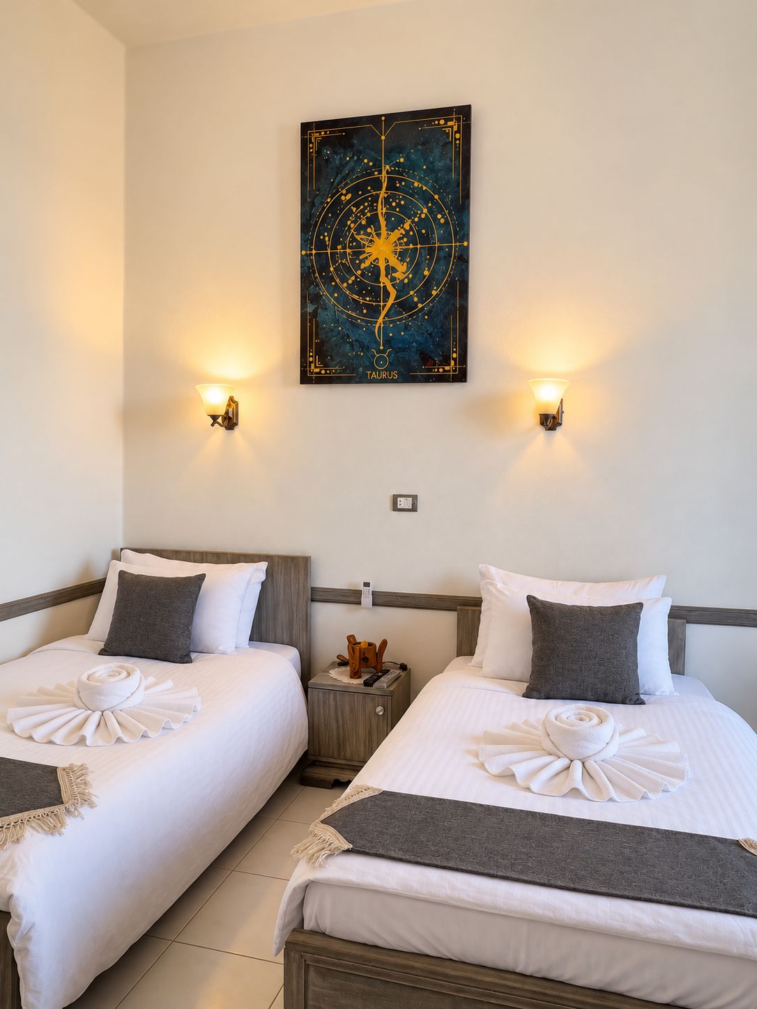 Een hotelkamer met twee bedden, een kunstwerk aan de muur en bedlampjes.