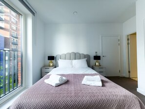 Ein Hotelzimmer mit einem Bett, zwei Nachttischen, einem Fenster und einer Tür.