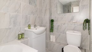 Ein Badezimmer mit Waschbecken, Spiegel, Toilette und einer Pflanze.