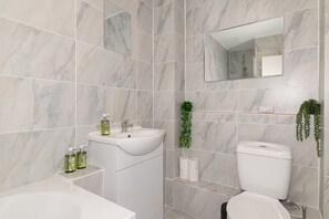 Ein Badezimmer mit Waschbecken, Spiegel, Toilette und einer Pflanze.