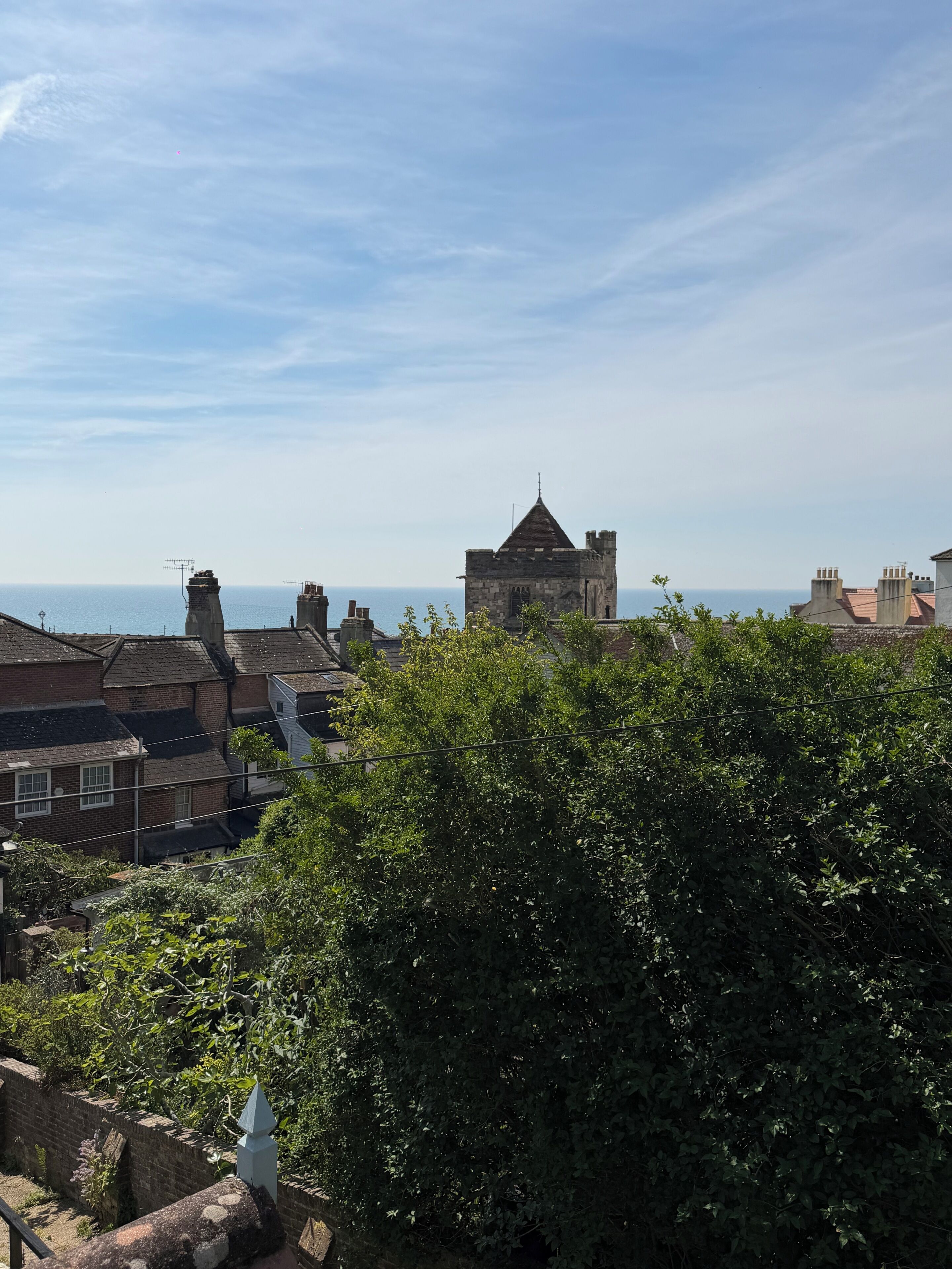 Une ville côtière dotée de bâtiments historiques en pierre, d’une tour imposante et offrant une vue sur la mer.