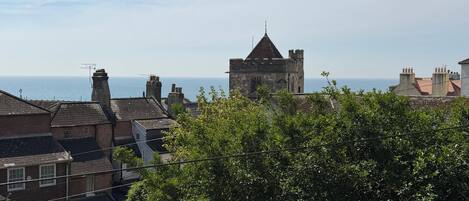 Une ville côtière dotée de bâtiments historiques en pierre, d’une tour imposante et offrant une vue sur la mer.