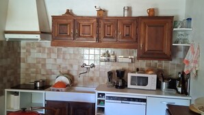 A compact kitchen with wooden cabinets, a microwave, a stove, and a dishwasher. - Authentic Vendée farmhouse set in a large wooded area 15 minutes from the sea (saint jean de monts)