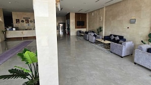 Un vestíbulo amplio con una recepción, zona de estar y una planta grande.