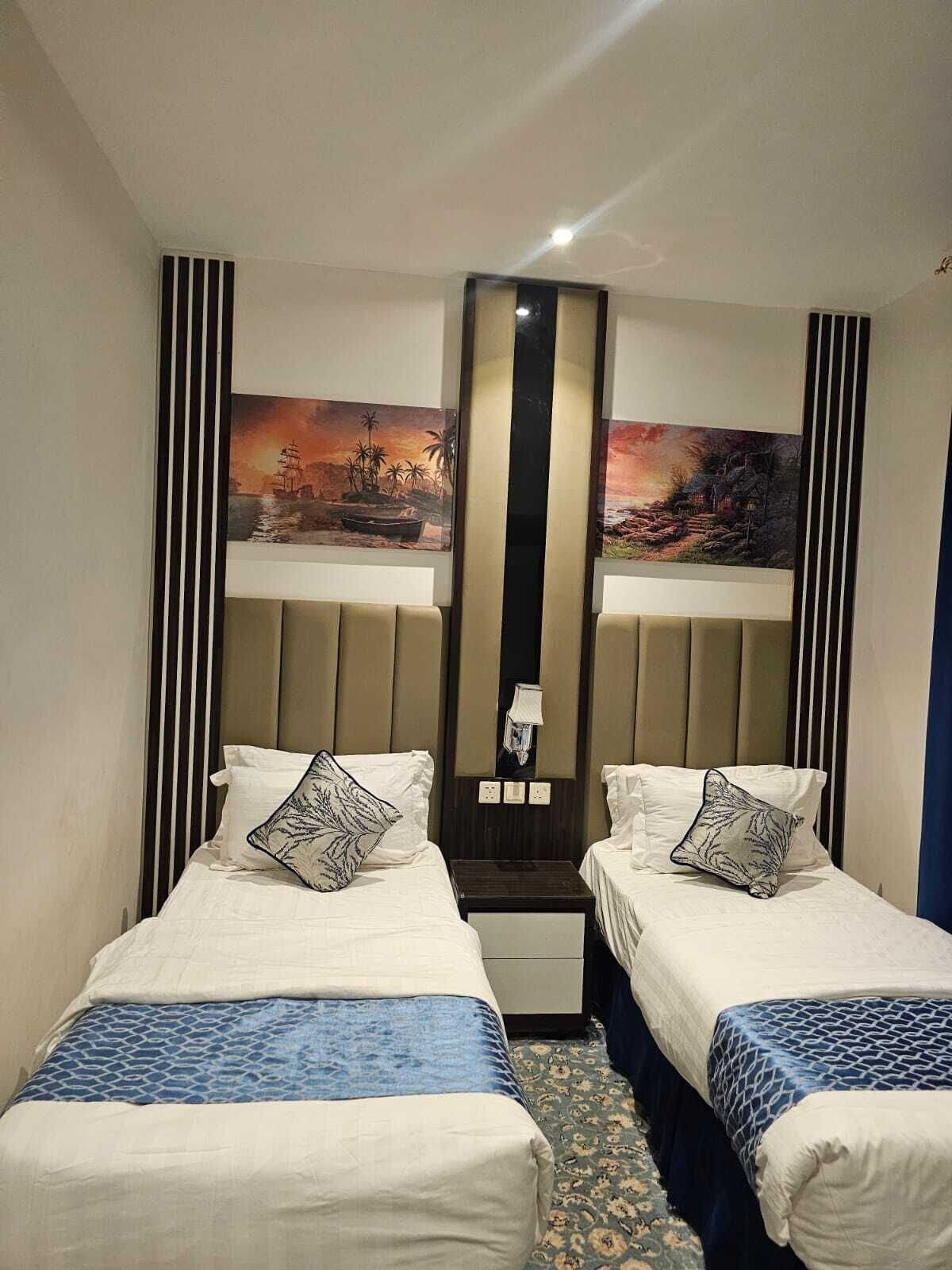 Une chambre d’hôtel avec deux lits, un grand miroir et deux tableaux accrochés au mur.