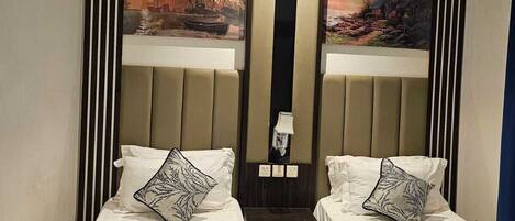 Une chambre d’hôtel avec deux lits, un grand miroir et deux tableaux accrochés au mur.
