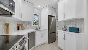 A modern kitchen with white cabinetry, stainless steel appliances, and a teal toaster. - Paradise Beach Getaway  Steps to Sand & Gulf Views  King Bed + Sofa Bed (Fort Myers Beach)