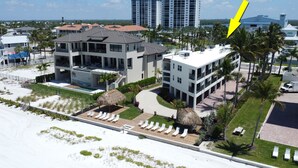 A modern hotel with a pool, multiple balconies, and a view of the beach. - Paradise Beach Getaway  Steps to Sand & Gulf Views  King Bed + Sofa Bed (Fort Myers Beach)