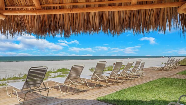 A beachside lounge with wooden deck chairs and a thatched roof overhead. - Paradise Beach Getaway  Steps to Sand & Gulf Views  King Bed + Sofa Bed (Fort Myers Beach)