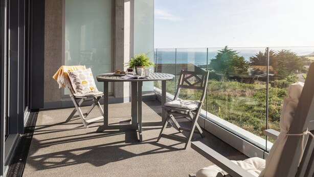 A balcony with two chairs, a table, and a potted plant. - Liner Apartment 17 (Falmouth)