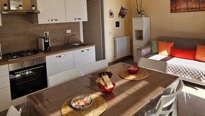 Uma cozinha moderna com armários brancos, uma mesa de jantar de madeira e um sofá na sala de estar.