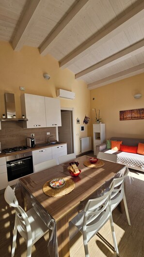 Eine moderne Küche mit weißen Schränken, einem Holzespeisetisch und einem Sofa im Wohnbereich.