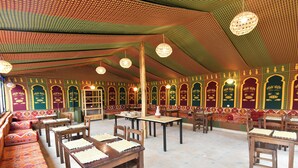 Een tentvormige constructie met tafels en stoelen binnen, voorzien van een patroon in het plafond en de wanden.