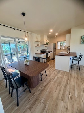 A modern kitchen with a central island, dining area, and a view of the outdoors. - Cozy Florida Home 2-bed / 1 bad with AC in charming Port Charlotte (Port Charlotte)
