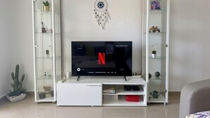 A living room with a flat-screen TV on a white entertainment unit, surrounded by glass-fronted shelving units with various decorative items. - Magnificent sea & golf views. Pools, Terraces (Asilah)