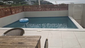En pool på taket med en blå uppblåsbar badring, ett träbord och en stol.