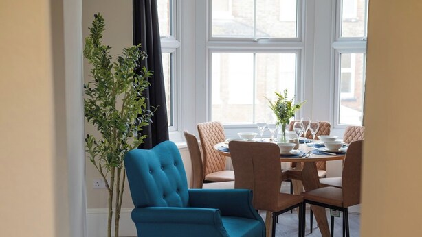 Een eetgedeelte met een ronde tafel, stoelen en een potplant.