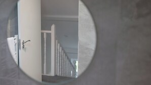 Een ronde spiegel weerspiegelt een trap en een deur, met een handdoek er hangend aan.