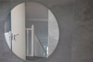Ein runder Spiegel, der eine Treppe und eine Tür mit einem daran hängenden Handtuch reflektiert.