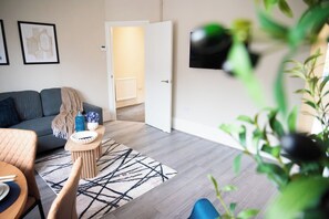 Ein Wohnzimmer mit einer Couch, einem Couchtisch, einem Teppich und einem Fernseher an der Wand.