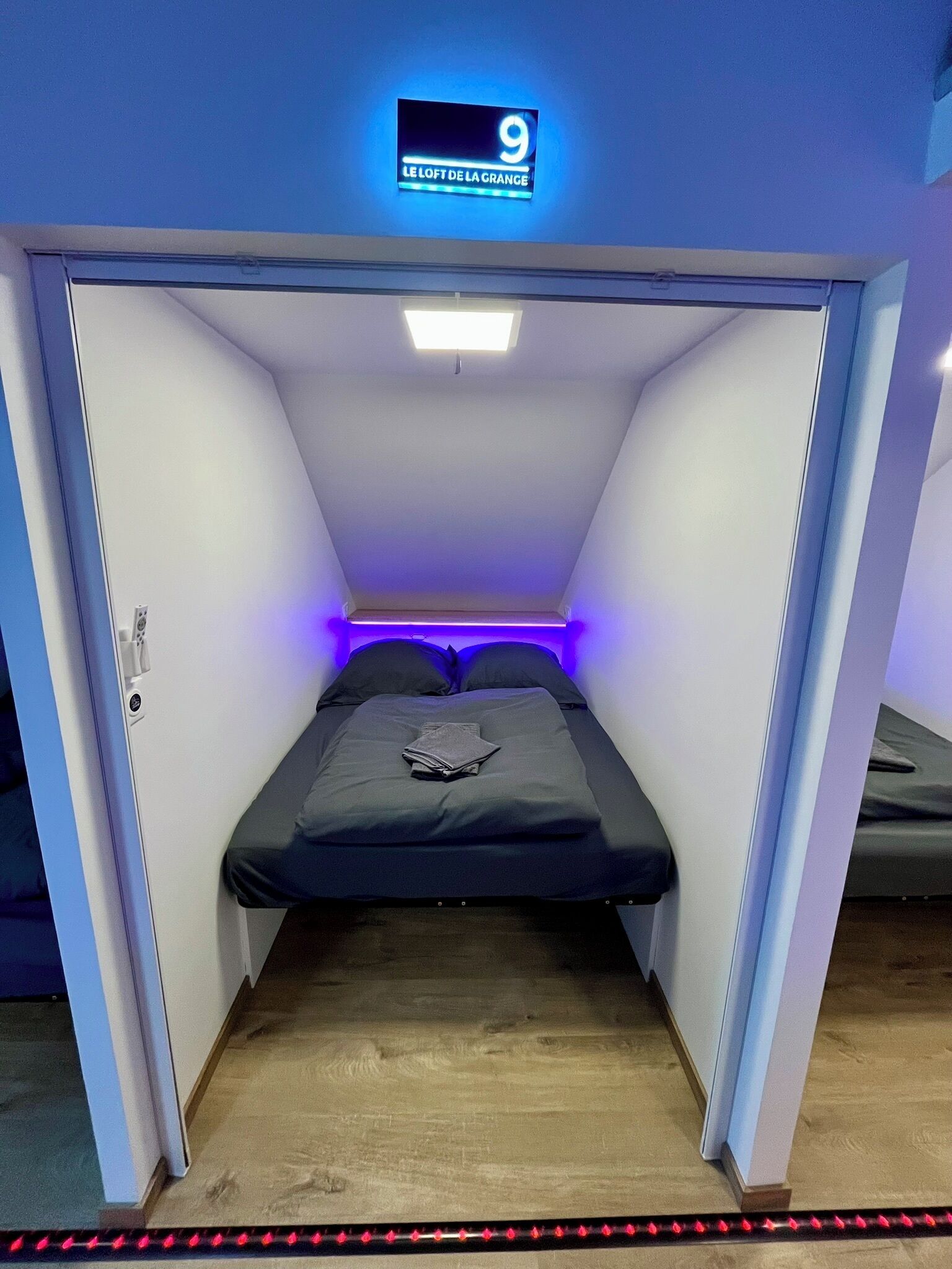A small, enclosed room with a bed, a ceiling light, and a sign with the number 9.