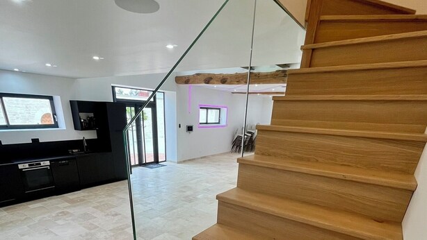 Ein modernes Interieur mit einer Holztreppe, einer Küchenzeile und einem Essbereich.