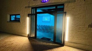 Ein Gebäudeeingang mit Glastür, kleinem Fenster und Backsteinboden.