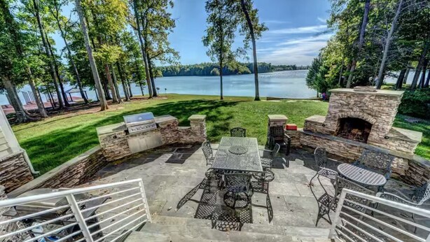 Un patio con muros de piedra, un hogar y vistas a un lago.