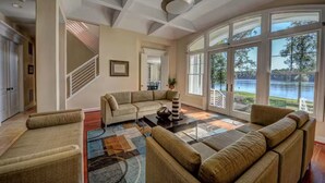 Amplia sala de estar con un ventanal grande, una escalera y vistas a un lago.