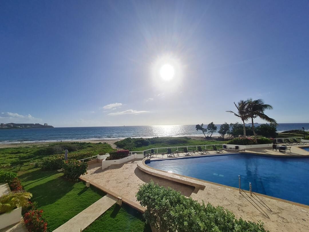 A swimming pool with a view of the ocean and a beach.