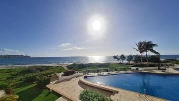 A swimming pool with a view of the ocean and a beach.