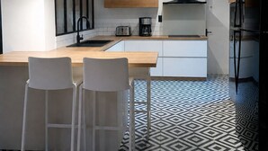 Een moderne keuken met hanglampen, een centraal eiland en een vloer met een patroon.