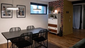 Een eetgedeelte met een tafel, stoelen, een boekenkast en een raam met natuurlijk licht.